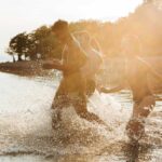 People running into the ocean at sunset